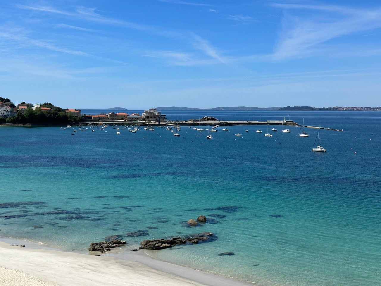 Discover the serene beauty of Ría de Vigo from a tranquil beach with clear waters and vibrant scenery.